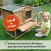A young girl is sitting next to a wooden rabbit hutch with an attached run, in a grassy backyard. Produktbild-Vorschau