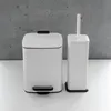 A white trash can and a white toilet brush holder are placed on a white surface against a gray concrete wall. Náhled obrázku produktu