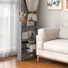 A narrow shelving unit with items on it, placed next to a sofa and a window with curtains. Náhled obrázku produktu