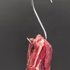 A close-up shot of a piece of raw meat hanging from a metal hook. Produktbild-Vorschau