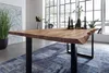 A dining table with a live edge top and black U-shaped legs, set in a modern dining room with large windows overlooking a body of water. Produktbild-Vorschau