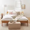A bed with pillows and blankets, a floor lamp, and a storage ottoman. Produktbild-Vorschau