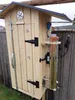 A wooden smoker with a stainless steel smoke generator attached to the side, set up outdoors next to a wooden fence. Anteprima dell’immagine prodotto