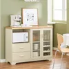 A cream-colored buffet cabinet with glass doors and drawers, featuring a microwave, coffee maker, and wine bottles, set in a room with light green walls and a wooden floor. Voir les images du produit