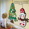 A young child is interacting with a DIY felt Christmas tree and snowman decoration set attached to a wall. Produktbild-Vorschau