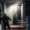 A burglar is shown attempting to break into a house at night, with a security camera and spotlight alarm system visible. Náhled obrázku produktu