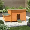A wooden chicken coop with a green roof and ramp, set on a paved patio with surrounding greenery. Anteprima dell’immagine prodotto