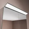 A close-up, angled view of the top of a mirrored cabinet with an integrated LED light. Náhled obrázku produktu