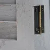 A close-up view of a hinge on a gray wooden shutter. Náhled obrázku produktu