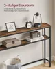 A narrow console table with two shelves, decorated with a framed picture, a clock, a lamp, a small radio, and a decorative box. A basket is visible at the bottom. Produktbild-Vorschau