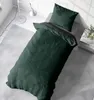 A bed with green bedding is shown in a room with a floor lamp. Produktbild-Vorschau