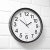 A round analog clock with a black frame and white face is mounted on a white tiled wall. Anteprima dell’immagine prodotto
