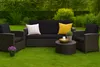 An outdoor furniture set including a sofa and two armchairs with cushions, placed on a green lawn with a hedge in the background. Voir les images du produit