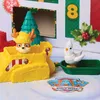 A close-up view of Paw Patrol toys, including a yellow bulldozer with a character wearing a reindeer hat, and a white bird in a green sled, set against a snowy background with elements of a Christmas advent calendar. Podgląd zdjęcia produktu