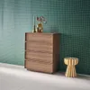 A wooden dresser with four drawers stands against a green tiled wall, next to a small stool. Anteprima dell’immagine prodotto