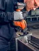 A person in work clothes and gloves is using a cordless reciprocating saw to cut metal. Produktbild-Vorschau