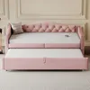 A pink upholstered daybed with a pull-out trundle bed is shown in a room with light-colored walls and a striped rug. Produktbild-Vorschau