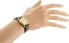 A woman's hand wearing a gold-colored watch with a brown leather strap. Produktbild-Vorschau