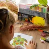 A young girl is coloring in a book with markers, with a set of markers in the background. Produktbild-Vorschau