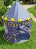 A children's play tent shaped like a castle is set up on a grassy lawn. Produktbild-Vorschau