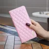 A pink quilted phone case held by a hand with dark nail polish. Produktbild-Vorschau
