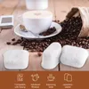 A coffee cup with a heart design on top, surrounded by coffee beans and a burlap sack, with three coffee filters in the foreground. Produktbild-Vorschau