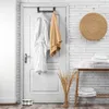 A bathroom scene with a door, towels, and a shelf with folded towels. Voir les images du produit