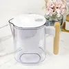 A water filter pitcher with a wooden handle sits on a marble countertop, with a vase of flowers in the background. Podgląd zdjęcia produktu