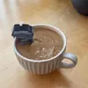 A small motor is attached to the rim of a mug filled with coffee, stirring it. Náhled obrázku produktu