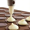 A close-up shot of a silicone baking mold being filled with batter from a piping bag. Podgląd zdjęcia produktu