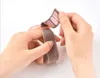 Hands attaching a pink and gray fabric watch band with velcro fasteners. Produktbild-Vorschau