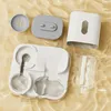 The image shows the disassembled parts of an automatic pet water dispenser and food feeder laid out on a textured, wavy yellow surface. Produktbild-Vorschau