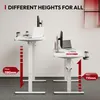Two white standing desks are shown in a modern office setting. The desk on the left is at a higher position than the desk on the right. Red arrows and text indicate the maximum and minimum height of the desks. Podgląd zdjęcia produktu