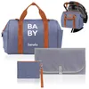 A collection of baby bag items including a large tote bag, a smaller pouch, and a changing mat, displayed against a white background. Náhľad obrázku produktu