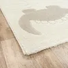 A close-up view of a rug with a pattern on a wooden floor. Produktbild-Vorschau