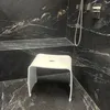 A white stool sits in a modern shower with black marble walls and floor. Produktbild-Vorschau