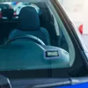 A digital parking disc is mounted on the dashboard of a car, visible through the windshield. Produktbild-Vorschau