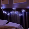 A string of starburst-shaped LED lights draped over a headboard above a bed. Produktbild-Vorschau