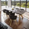A dining room with a table and chairs set up, with large windows overlooking a natural landscape. Náhled obrázku produktu