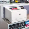 A white HP printer is shown on a shelf with dimensions indicated by lines and text. Podgląd zdjęcia produktu