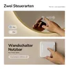 A split image showing two ways to control a mirror's features: the top half shows a hand touching a mirror's illuminated display, and the bottom half shows a hand pressing a wall switch. Produktbild-Vorschau