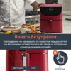 A person's hands are shown near a red air fryer, with food in bowls in the foreground. Produktbild-Vorschau