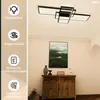 A modern geometric ceiling lamp is shown installed on a ceiling above a wooden cabinet with artwork and decorative items. Voir les images du produit