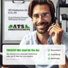 A man wearing a headset is smiling and looking at the camera, with a sign in the background that has company information and a logo. Produktbild-Vorschau