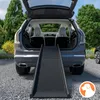 A dog ramp is placed in the open trunk of a car, leading out to the ground. Produktbild-Vorschau