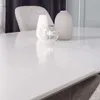A close-up view of a white dining table with decorative items on it, including vases and a candle holder. Produktbild-Vorschau