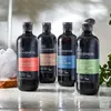 Four bottles of men's body wash are arranged on a wet surface, possibly in a shower. There is a loofah and some greenery in the background. Produktbild-Vorschau