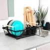 A dish drying rack with plates, cutlery, and glasses next to a kitchen sink. Náhled obrázku produktu
