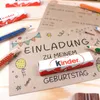 Birthday invitation cards with Kinder chocolate bars and colored pencils on a wooden surface. Produktbild-Vorschau