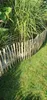 A wooden picket fence in a garden with tall grass behind it. Produktbild-Vorschau